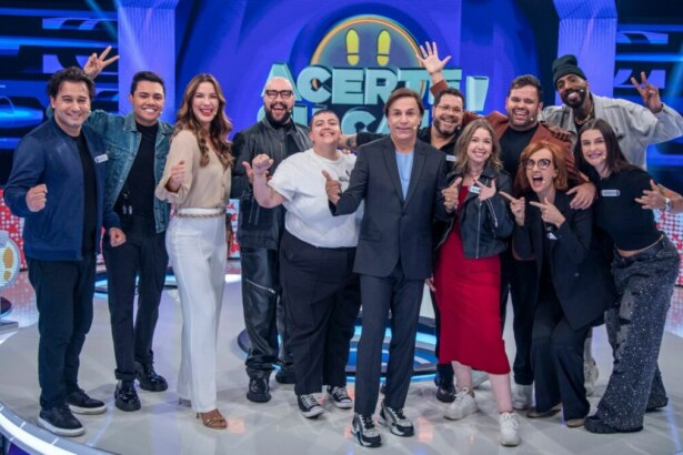 Tom Cavalcante com o elenco do programa Acerte ou Caia, todos sorrindo e posando juntos no palco.
