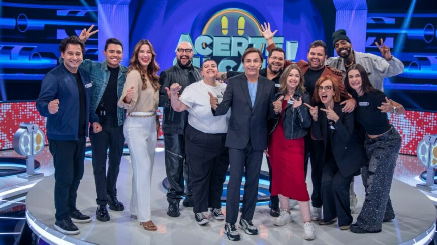 Tom Cavalcante com o elenco do programa Acerte ou Caia, todos sorrindo e posando juntos no palco.