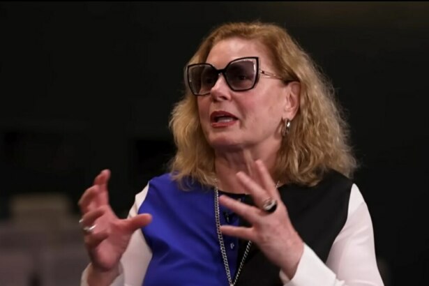 A atriz Vera Fischer, com cabelos loiros e ondulados, sorri para a câmera durante uma entrevista para o programa Domingo Espetacular.