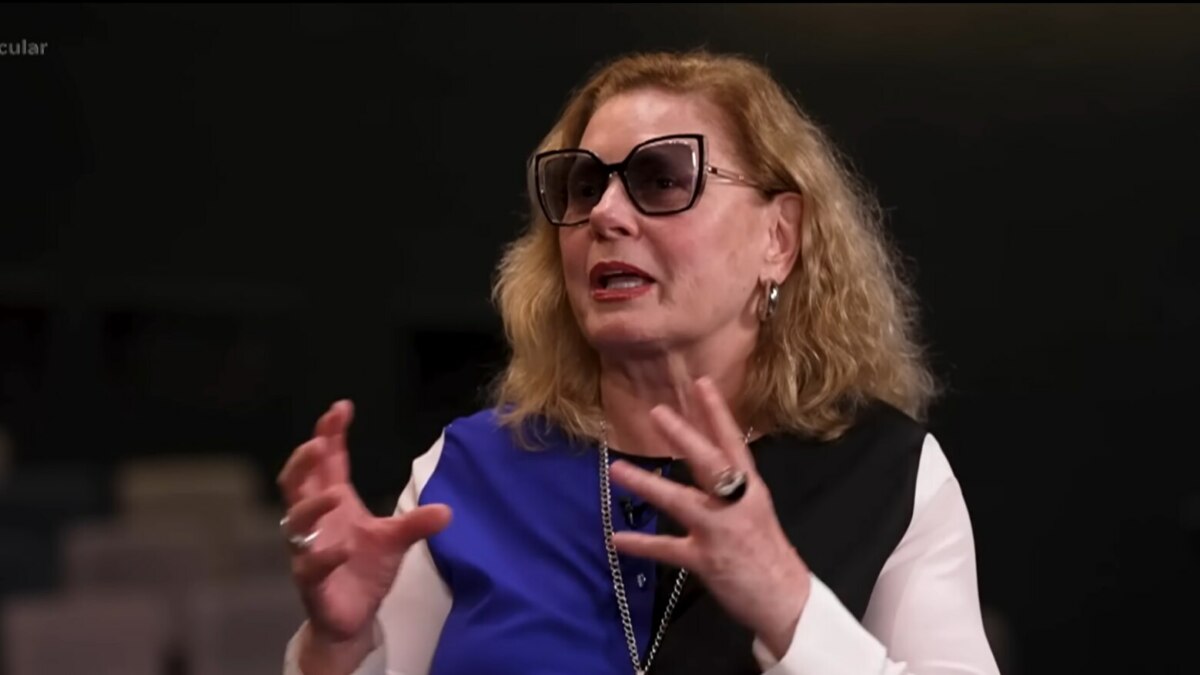 A atriz Vera Fischer, com cabelos loiros e ondulados, sorri para a câmera durante uma entrevista para o programa Domingo Espetacular.