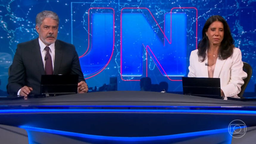 William Bonner e Mônica Teixeira sentados na bancada do Jornal Nacional