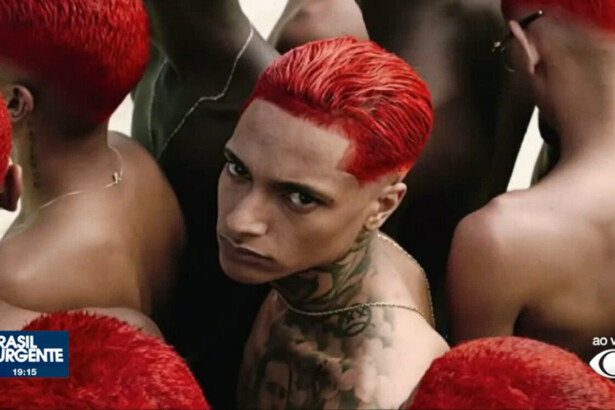 Oruam de cabelo vermelho e com tatuagem no ombro e pescoço