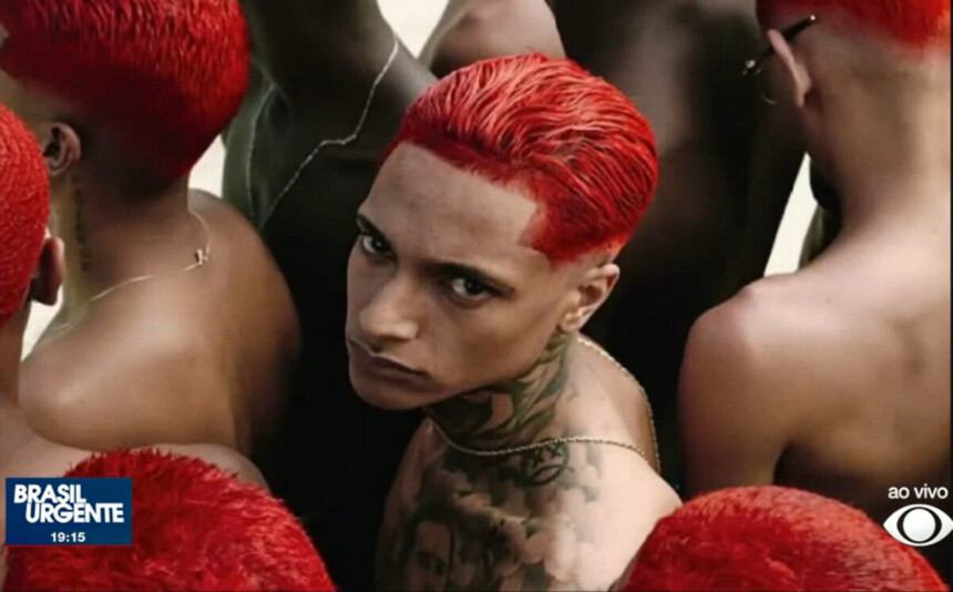 Oruam de cabelo vermelho e com tatuagem no ombro e pescoço