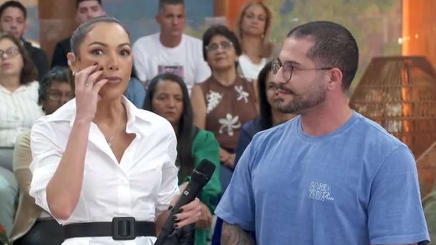 Patrícia Poeta mostrando algo no rosto, ao lado de um convidado no Encontro