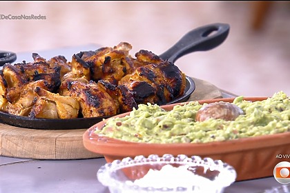 Sobrecoxa com iogurte na churrasqueira, molho tzatziki e guacamole do Thiago Oliveira em cima da mesa do É De Casa